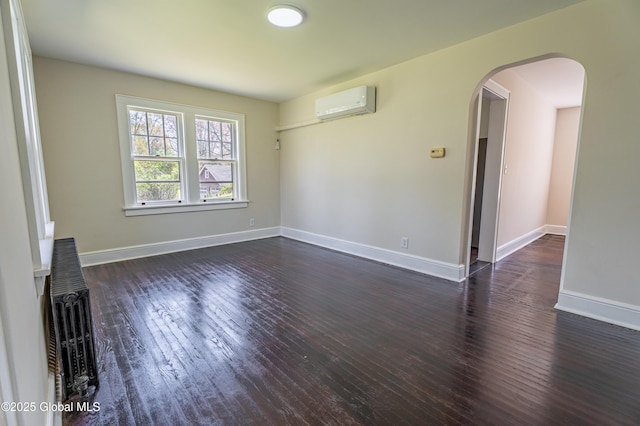unfurnished living room with dark wood-type flooring, a wall mounted air conditioner, baseboards, and arched walkways