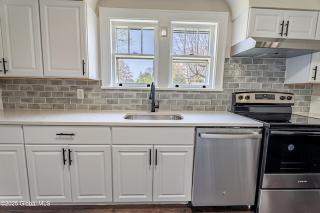 kitchen featuring a sink, stainless steel appliances, white cabinetry, decorative backsplash, and under cabinet range hood