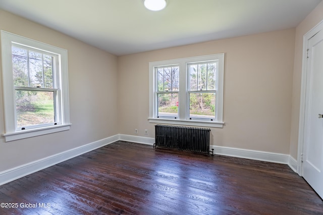 empty room featuring baseboards, dark wood-style floors, and radiator
