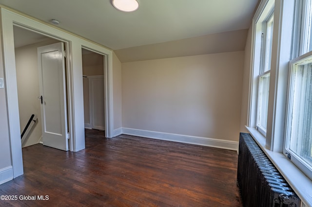interior space featuring radiator heating unit, baseboards, vaulted ceiling, and dark wood-style flooring