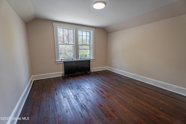 additional living space with baseboards, dark wood-style flooring, radiator heating unit, and vaulted ceiling