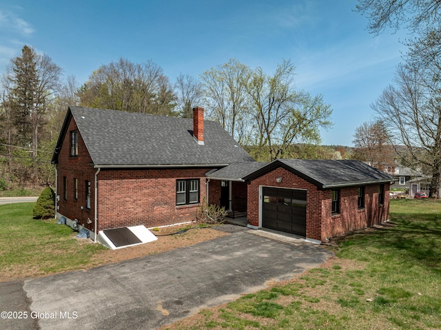 view of front of home featuring aphalt driveway, a front yard, a chimney, brick siding, and an attached garage