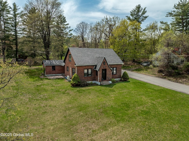 view of front of home with brick siding, a shingled roof, and a front yard