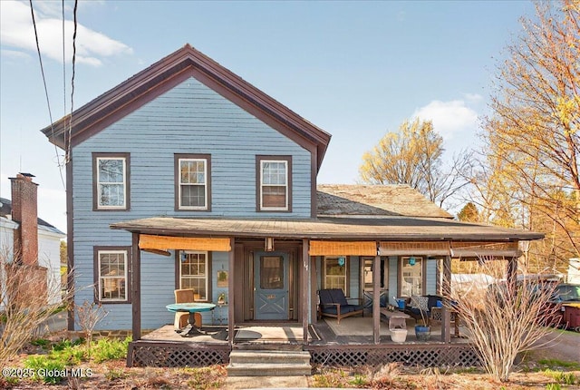 view of front facade with a shingled roof and covered porch