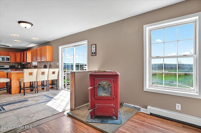 346 State Route 197, Fort Edward, NY 12828 - interior space featuring a kitchen breakfast bar, stainless steel microwave, a wood stove, baseboard heating, and a peninsula