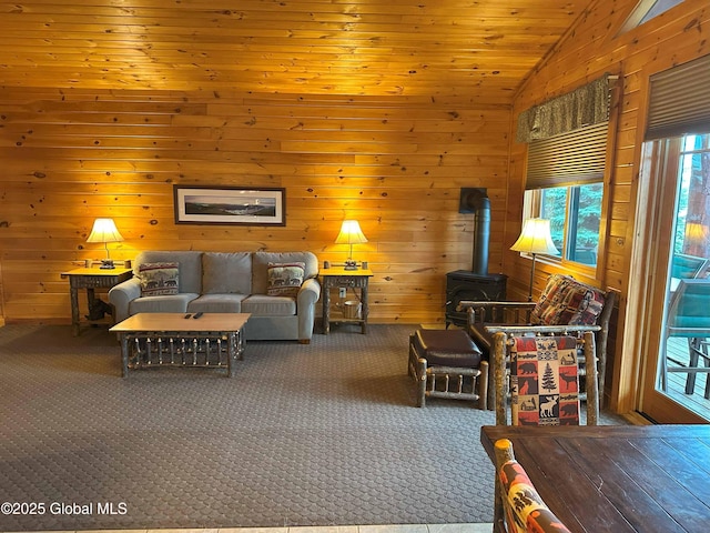 living room with a wood stove, carpet, vaulted ceiling, and a healthy amount of sunlight