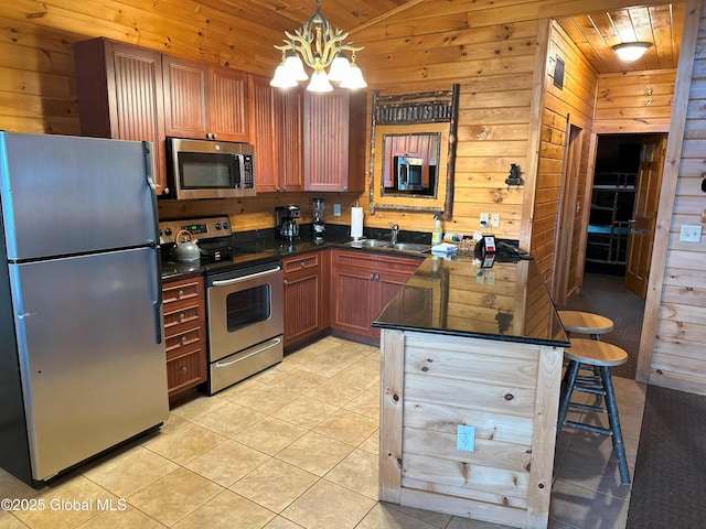 kitchen featuring appliances with stainless steel finishes, wooden walls, and a sink