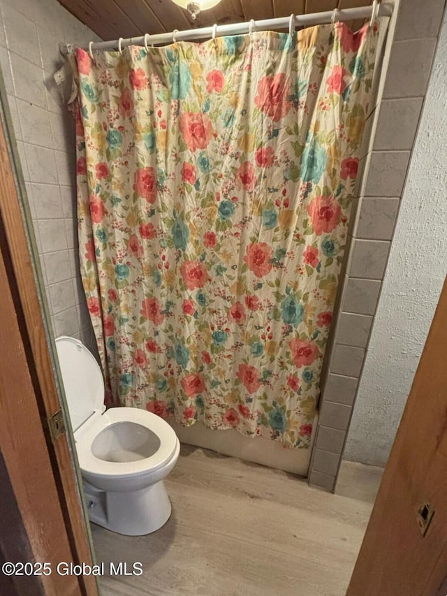 full bath featuring toilet, shower / tub combo with curtain, and wood finished floors