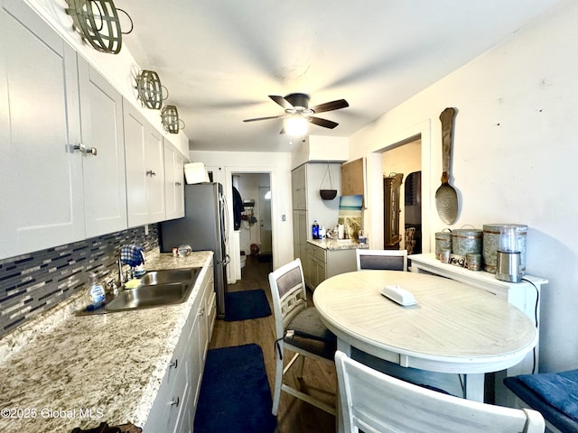 kitchen featuring a ceiling fan, a sink, dark wood finished floors, white cabinetry, and decorative backsplash