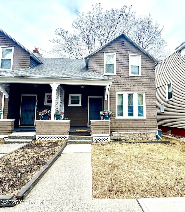 view of front of home with a chimney, a porch, and a shingled roof