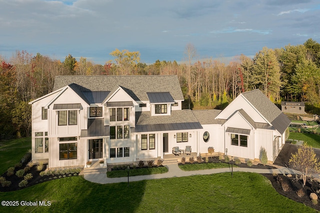 rear view of property with a standing seam roof and a lawn