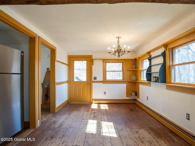 unfurnished dining area with hardwood / wood-style floors, baseboards, an inviting chandelier, and a baseboard radiator