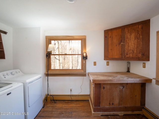 clothes washing area featuring a baseboard heating unit, cabinet space, washing machine and dryer, baseboards, and wood finished floors