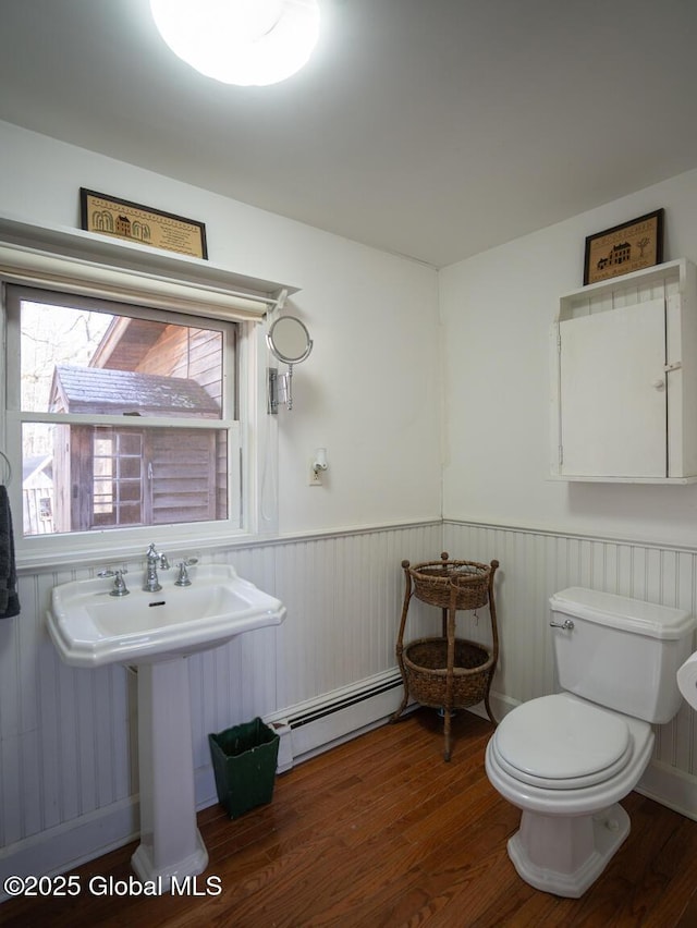 bathroom featuring wainscoting, wood finished floors, toilet, and a baseboard radiator