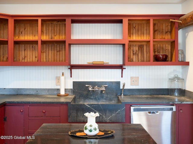 kitchen featuring stainless steel dishwasher, dark countertops, a sink, and open shelves