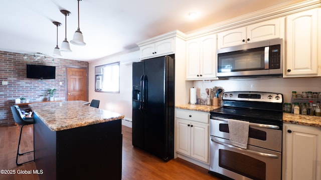 kitchen featuring a center island, cream cabinets, light stone counters, dark wood finished floors, and stainless steel appliances