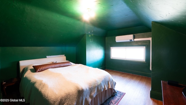 bedroom with wood finished floors, baseboards, lofted ceiling, and a wall unit AC