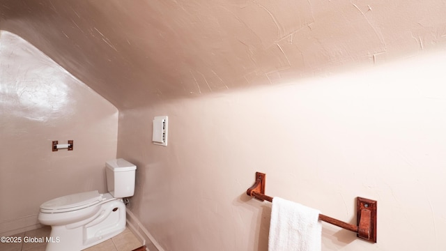 bathroom featuring toilet, baseboards, tile patterned flooring, and lofted ceiling