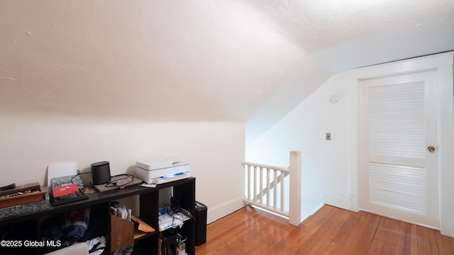 home office with baseboards, vaulted ceiling, and light wood finished floors