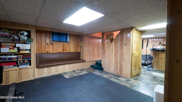 finished basement with wooden walls and a drop ceiling