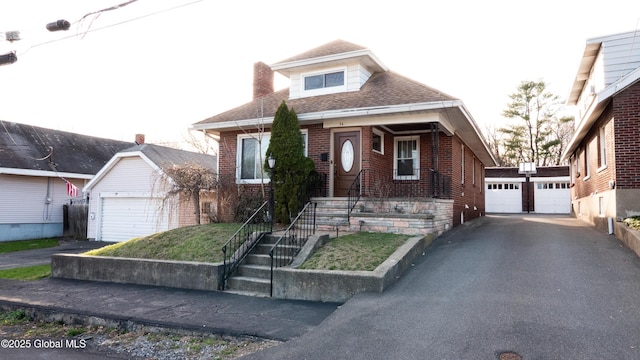 bungalow-style house with brick siding, an outdoor structure, roof with shingles, and a garage