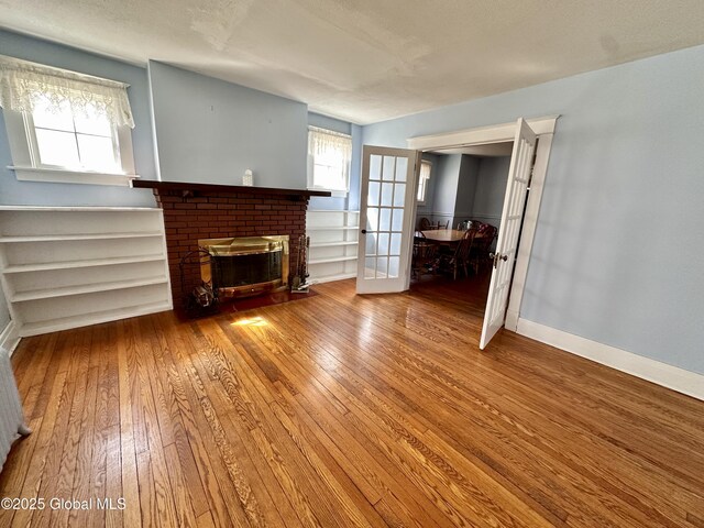 11 Middlesex Rd, East Greenbush, NY 12061 - unfurnished living room with baseboards, wood-type flooring, plenty of natural light, and a brick fireplace