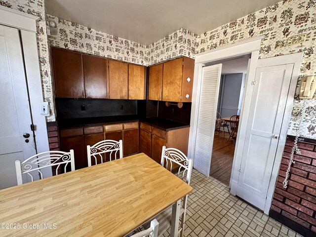 11 Middlesex Rd, East Greenbush, NY 12061 - kitchen with brick floor, dark countertops, brown cabinetry, and wallpapered walls