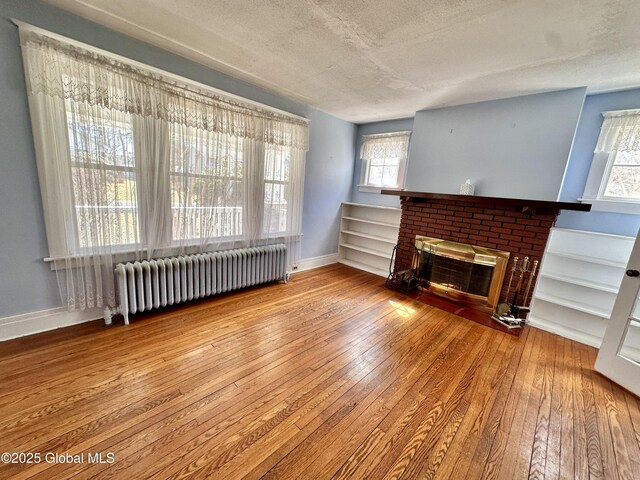 11 Middlesex Rd, East Greenbush, NY 12061 - unfurnished living room with hardwood / wood-style floors, radiator heating unit, a fireplace, and a textured ceiling