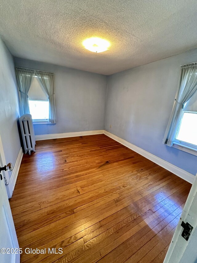 11 Middlesex Rd, East Greenbush, NY 12061 - spare room featuring a textured ceiling, radiator heating unit, baseboards, and hardwood / wood-style flooring
