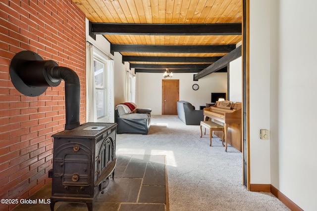 living room featuring carpet, beamed ceiling, wood ceiling, a wood stove, and brick wall