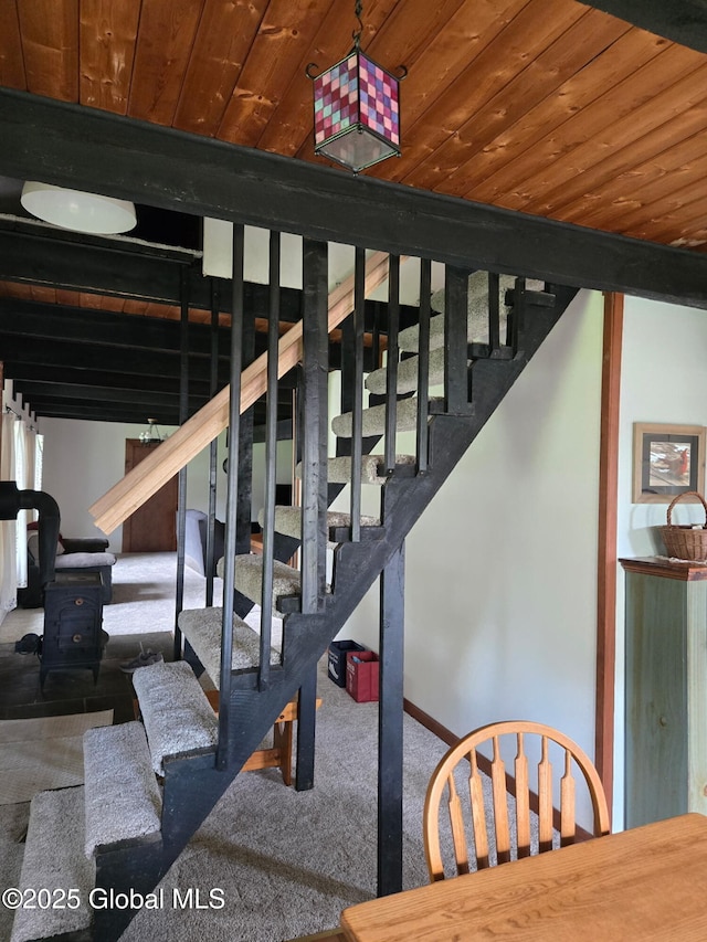 stairway with wooden ceiling, carpet flooring, a wood stove, and baseboards