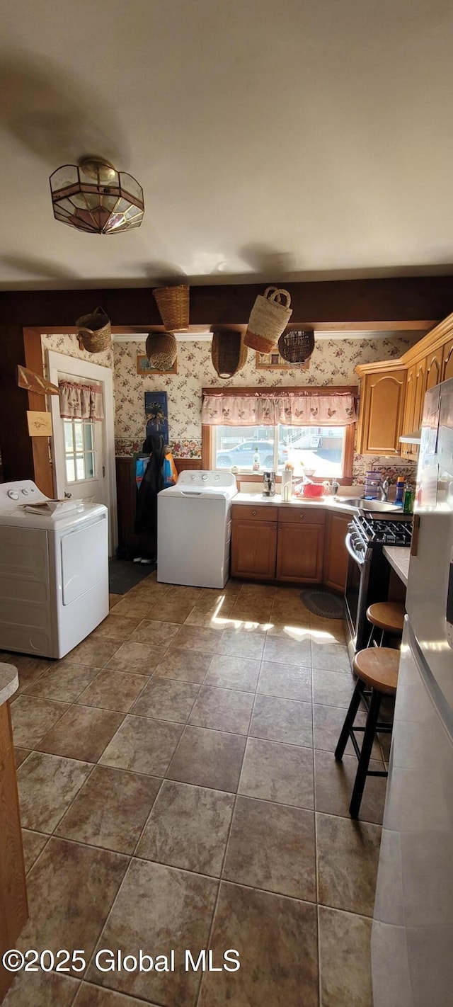 755 County Route 7, Schodack, NY 12063 - kitchen featuring washer and dryer, wallpapered walls, stainless steel range with gas cooktop, and light countertops