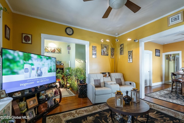 living room with crown molding, wood finished floors, baseboards, and ceiling fan