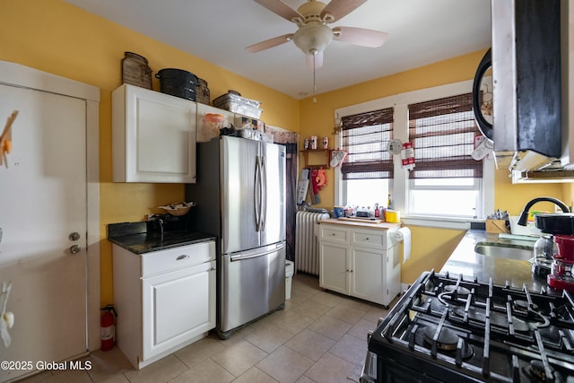 kitchen with a ceiling fan, a sink, white cabinetry, gas stove, and freestanding refrigerator