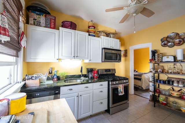 kitchen with light tile patterned flooring, white cabinets, stainless steel appliances, and a sink