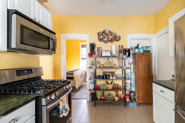 kitchen featuring white cabinetry, dark countertops, light tile patterned flooring, and stainless steel appliances