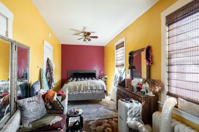 bedroom with radiator, multiple windows, and a ceiling fan