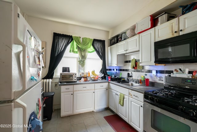 kitchen featuring a sink, white cabinetry, freestanding refrigerator, black microwave, and gas range