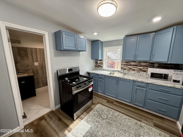 9 Brandt Pl, Amsterdam, NY 12010 - kitchen with a sink, blue cabinetry, white microwave, and stainless steel gas range oven