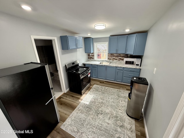 9 Brandt Pl, Amsterdam, NY 12010 - kitchen featuring blue cabinets, backsplash, appliances with stainless steel finishes, and wood finished floors