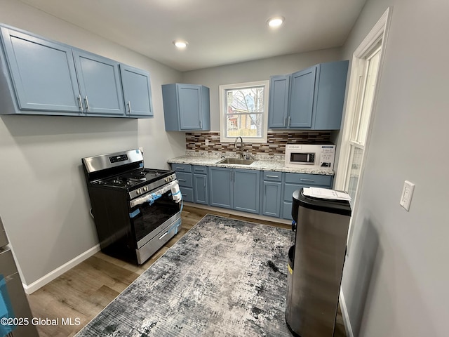 9 Brandt Pl, Amsterdam, NY 12010 - kitchen with white microwave, tasteful backsplash, stainless steel range with gas cooktop, light wood-style flooring, and blue cabinets