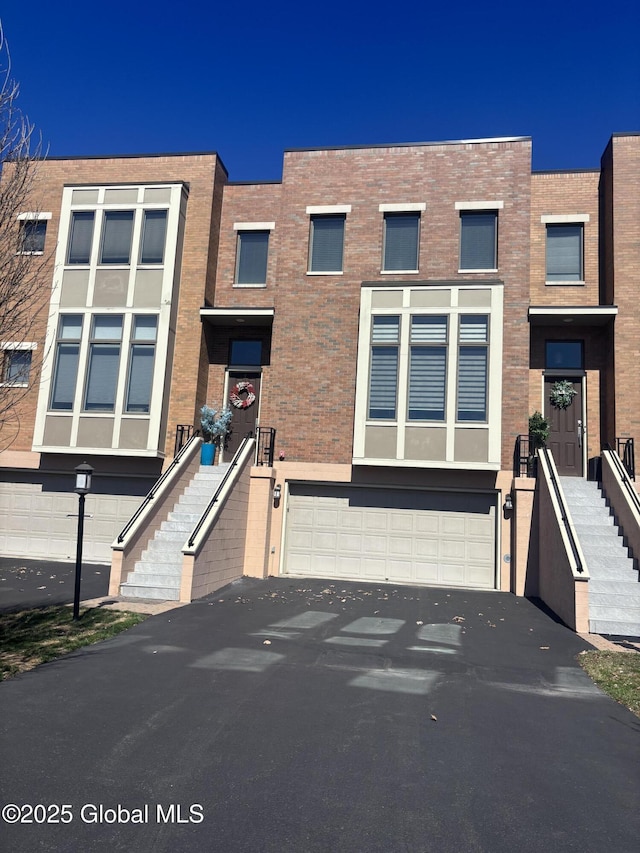 multi unit property featuring a garage, brick siding, and aphalt driveway