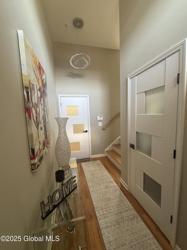 corridor featuring stairs, baseboards, and wood finished floors