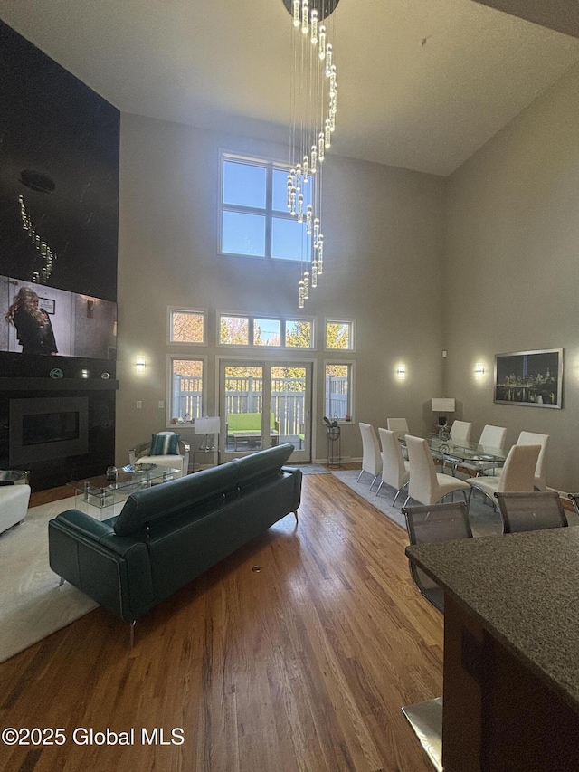 living area with a notable chandelier, a high ceiling, and wood finished floors