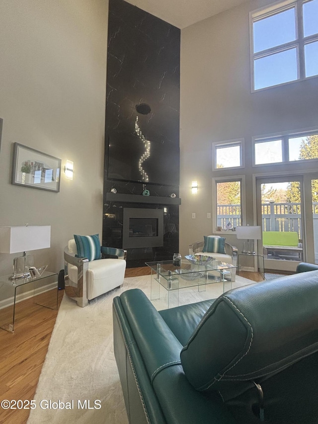 living room with wood finished floors, baseboards, and a towering ceiling