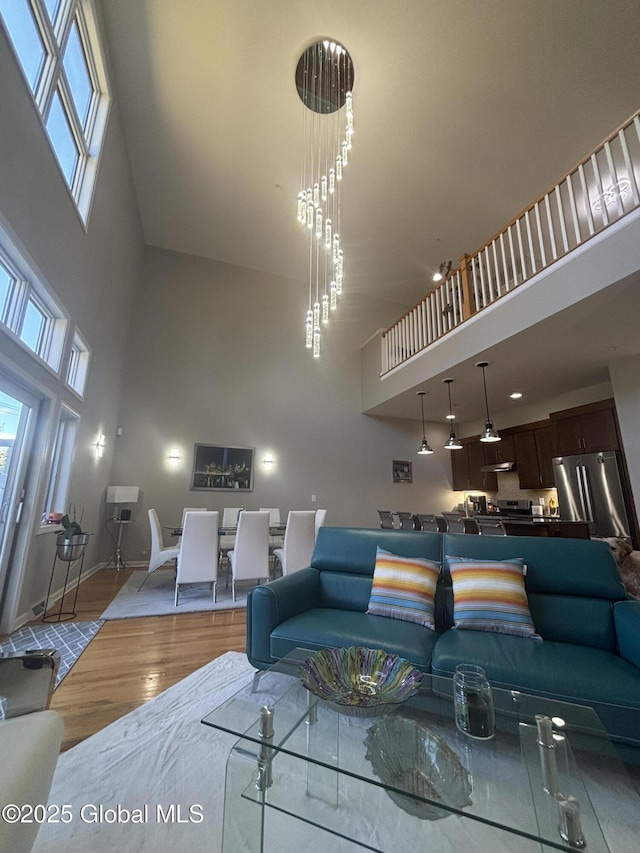 living area with baseboards, a high ceiling, and wood finished floors