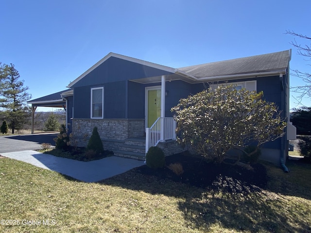 view of side of property featuring stone siding, an attached carport, and a yard