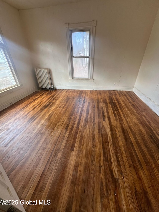 unfurnished room with radiator, plenty of natural light, and wood-type flooring