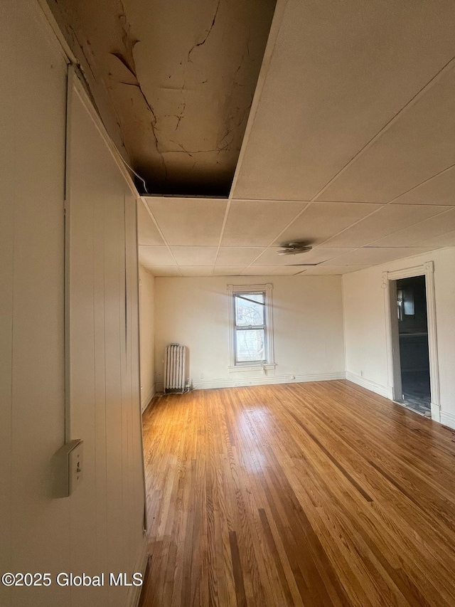 unfurnished room featuring radiator, baseboards, and wood finished floors