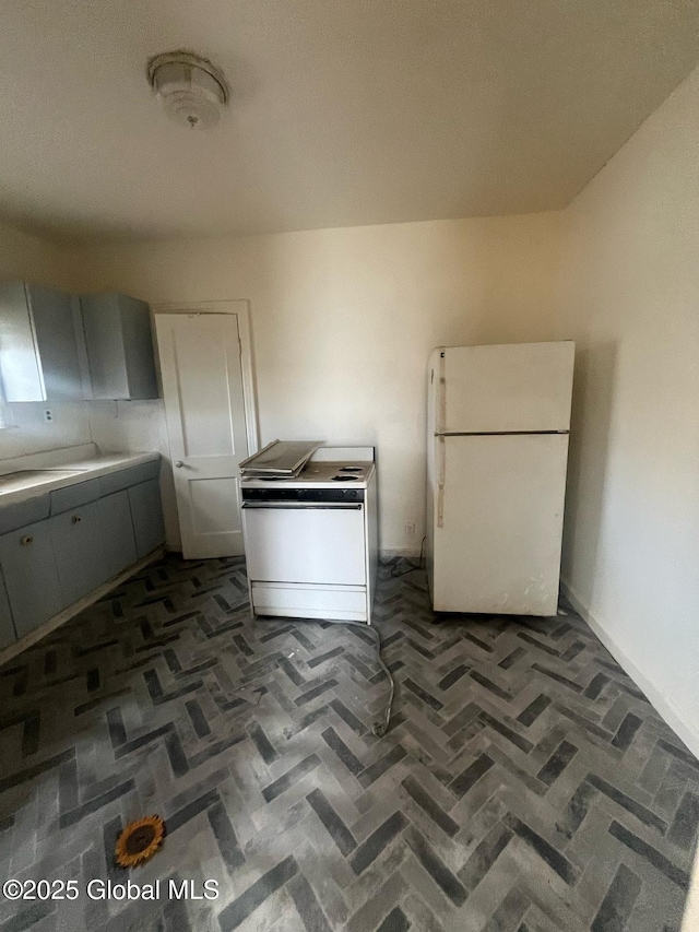 kitchen featuring range, brick floor, and freestanding refrigerator